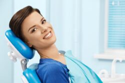 woman in blue shirt sitting in dental chair with bib root canal restorative dentistry dentist in Viera Florida